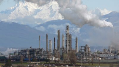 Oil refinery with distillation towers and steam against mountains