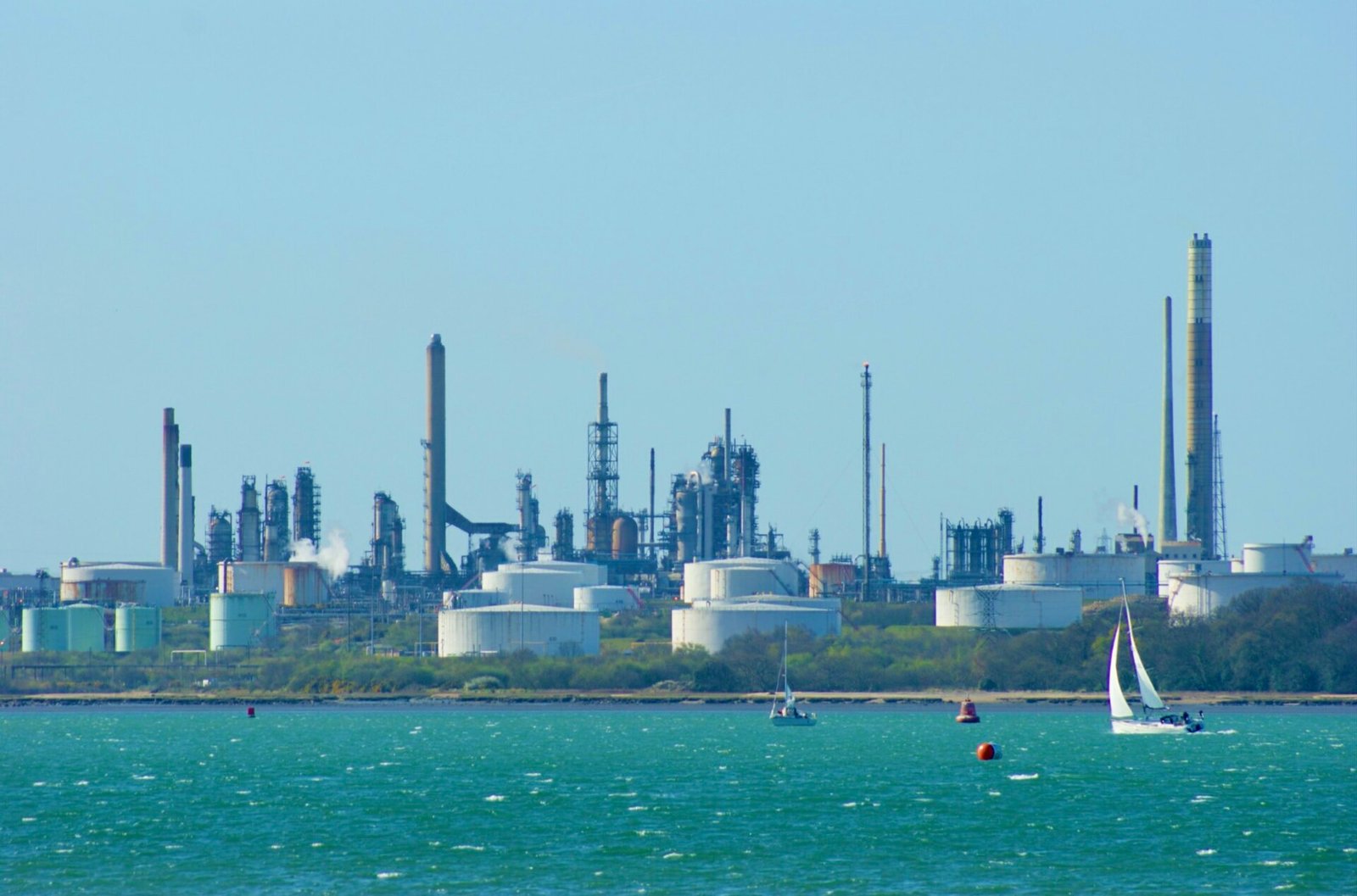 Oil refinery complex with storage tanks viewed from the water